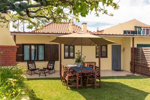 a table with an umbrella in the yard of a house at Casa da Varzinha in A dos Cunhados