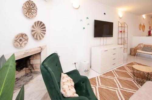 a living room with a fireplace and a green chair at Windmill by OCvillas in Albufeira