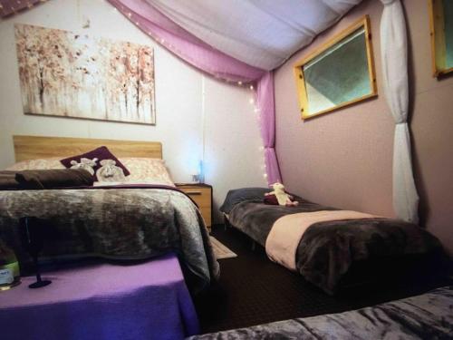 a bedroom with two beds in a room with purple walls at Cosy woodland Romantic retreat With log fires and nature in Sturry