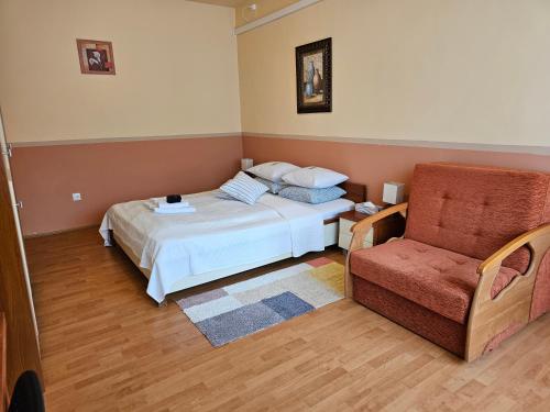 a bedroom with a bed and a chair at Abigél 2 Vendégház in Miskolctapolca