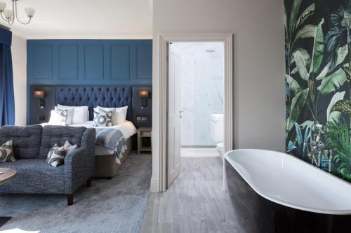 Aysgarth Falls Hotel & Restaurant في إيسجارث: حمام به سرير وحوض استحمام بجانب غرفة نوم