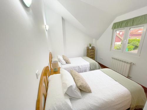 2 camas en una habitación blanca con ventana en Casa de Anmar casa independiente con jardín, Ajo, en Ajo