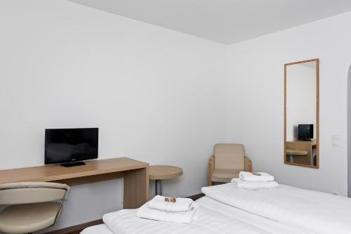 a room with two beds and a desk and a mirror at Hotel Adler in Friedrichshafen