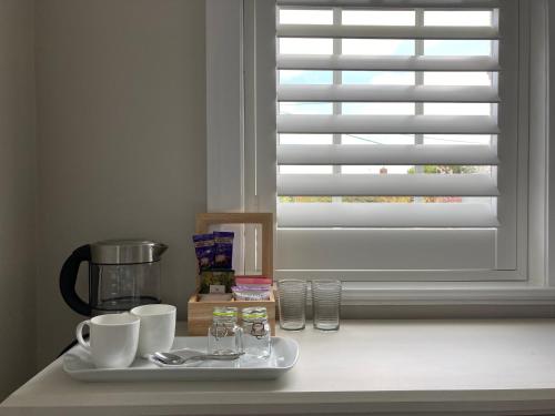 a table with a tray with cups and a window at The Old Bell B&B in Grimston