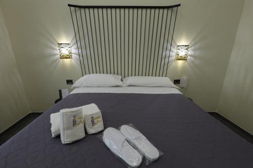 a bedroom with a bed with towels and slippers on it at Il Salotto della Regina in Naples