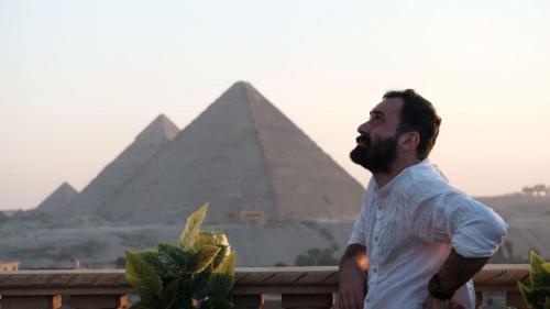 un hombre parado frente a las pirámides en Crowne Pyramids view inn en El Cairo