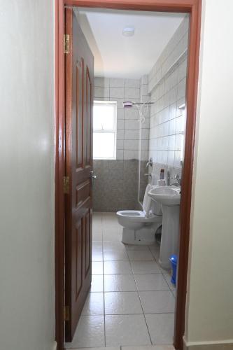 baño con aseo, lavabo y puerta en The Light House Nanyuki. Captivating 2 bedroom, en Nanyuki