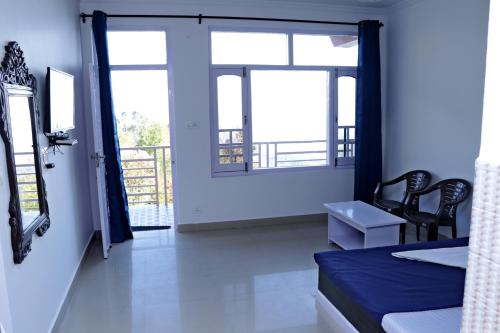 1 Schlafzimmer mit einem Bett und 2 Stühlen sowie einem Balkon in der Unterkunft Himalayan Homestay in Dharamshala