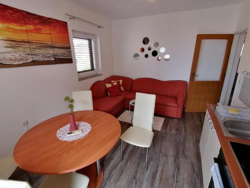 a living room with a table and a red couch at Splendid Sea View Apartment Marko in Novalja