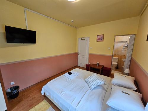 a bedroom with a bed and a tv on the wall at Abigél 2 Vendégház in Miskolctapolca