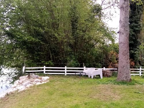 a white bench next to a fence and a tree at Havre de paix au bords de l'Eure - divers hébergements in Neuilly
