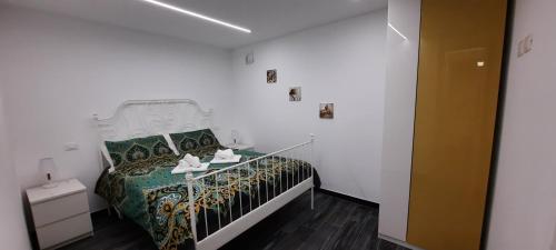 a white bedroom with a bed with a white and green bedspread at Appartamento Ambrosia in Manarola