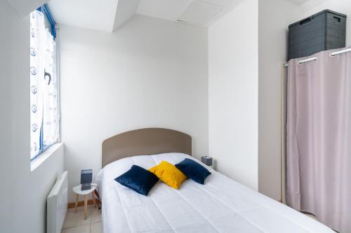 een slaapkamer met een bed met twee blauwe en gele kussens bij Vacances en duo au Guilvinec ! in Le Guilvinec