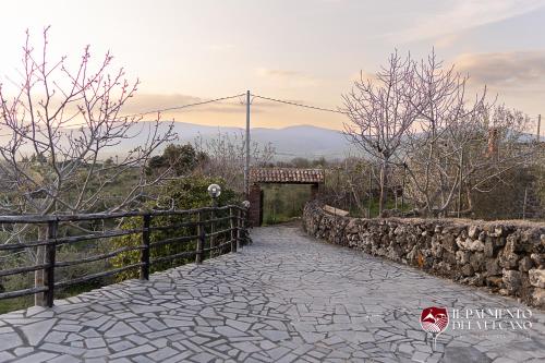 a stone walkway with a stone wall and a gate at Chalet il Palmento del Vulcano in Bronte