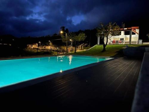 a blue swimming pool at night with a house at CASA DA CASTANHEIRA in Candeiro