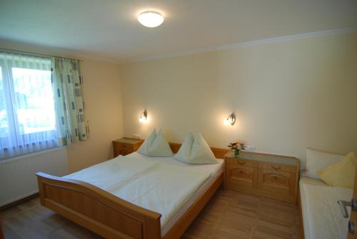 a bedroom with a bed with white sheets and a window at Ferienwohnung Stöckl in Leogang