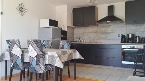 une cuisine avec une table et des chaises dans l'établissement Les 2 rivières Auray-Pluneret dans le Golfe du Morbihan, à Pluneret