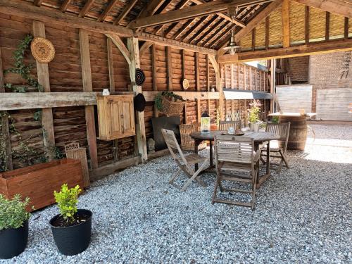 un patio con mesa y sillas en un granero en Gîte "Au dépôt" en Mesnières-en-Bray