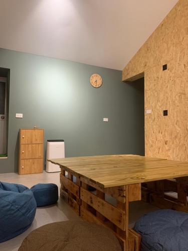 Habitación con mesa de madera y reloj en la pared en zouzou hostel, en Isla Verde