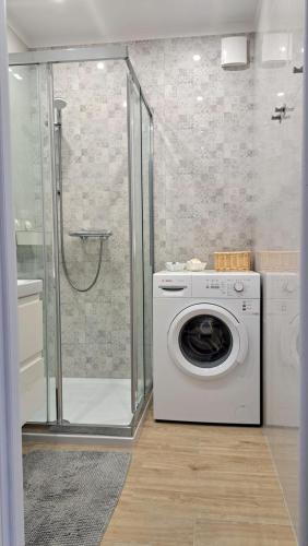 a washing machine in a bathroom with a shower at Apartament Między Jeziorami in Augustów