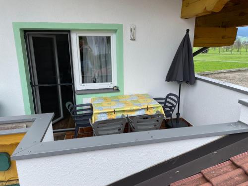 a table and chairs on a balcony with an umbrella at Landhaus Sonne in Maishofen
