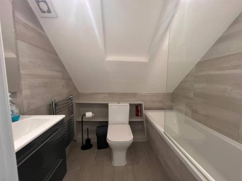 La salle de bains est pourvue de toilettes, d'un lavabo et d'une baignoire. dans l'établissement Star London Finchley Road 3-Bed Haven, à Londres
