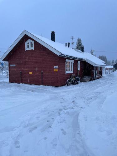 a red barn in the snow with a snow covered driveway at Yllästölli 2 A, Äkäslompolo in Kolari