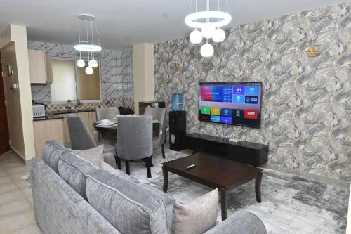 a living room with a couch and a tv on a wall at Greybun House 1 Bedroom in Nanyuki