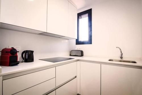 cocina con armarios blancos, fregadero y ventana en 4-1 Apartamento de diseño en el centro de Reus en Reus