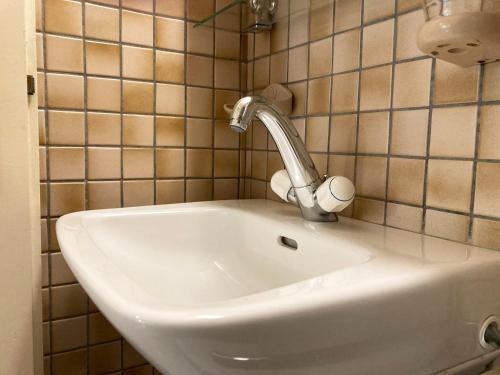 - białą umywalkę w łazience ze ścianami wyłożonymi kafelkami w obiekcie Les Ouches w mieście Saint-Blaise