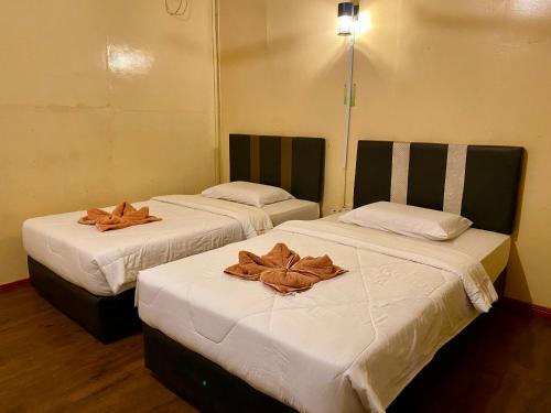 Dos camas en una habitación con toallas marrones. en Sukau Greenview Bed & Breakfast, en Sukau
