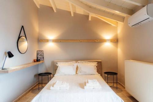 a bedroom with a white bed with two stools at Inalia Modern House in Lefkimmi