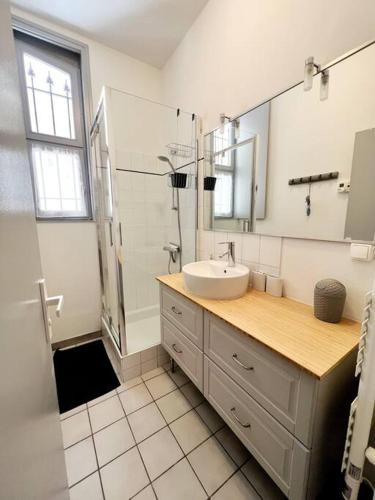 une salle de bain avec un lavabo et une douche avec un miroir dans l'établissement Cour Passy - Centre ville, à La Rochelle
