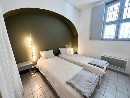 une chambre avec deux lits et une grande fenêtre dans l'établissement Cour Passy - Centre ville, à La Rochelle