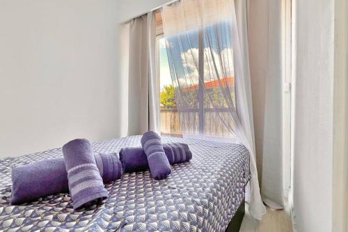 a bed with purple pillows in a room with a window at Le Mistral in Nice