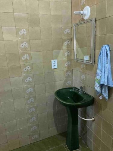 a bathroom with a green sink and a mirror at Casinha Valdenia: No paraíso com Wi-Fi, em Mundaú in Trairi