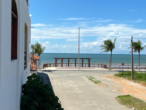 an empty road next to the ocean with palm trees at Casinha Valdenia: No paraíso com Wi-Fi, em Mundaú in Trairi