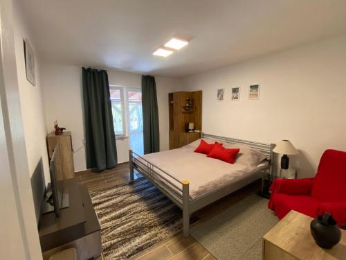 1 dormitorio con 1 cama y 1 silla roja en Eszter Apartman, en Balatonmáriafürdő