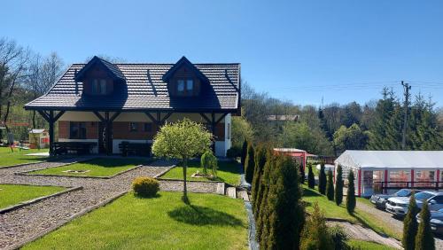 a house with a gambrel roof on top of a yard at Słoneczna Polana in Solina
