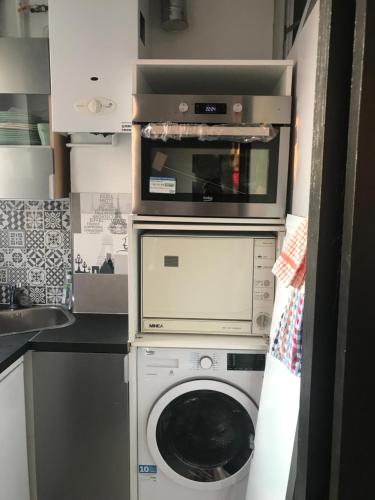 une cuisine avec un lave-linge et un micro-ondes dans l'établissement Appart douillet Paris 11, à Paris
