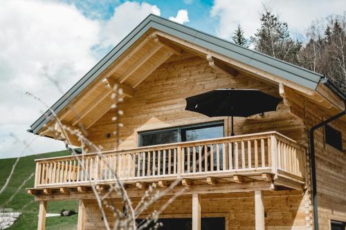 a log cabin with a balcony and an umbrella at Chalet 49 Nesselgraben - Ferienwohnungen aus Holz in Koppl