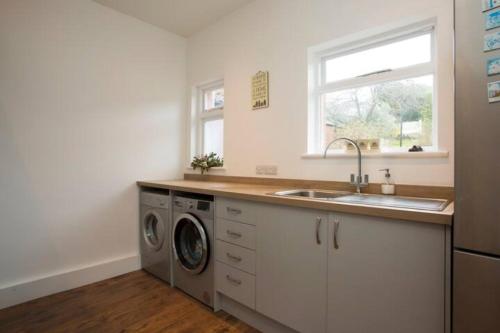 a kitchen with a sink and a washing machine at Rie's Retreat - The Emerald room in Glastonbury
