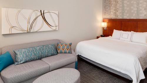 une chambre d'hôtel avec un lit et un canapé dans l'établissement Courtyard by Marriott Pittsburgh West Homestead Waterfront, à West Homestead