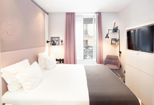 ein Hotelzimmer mit einem weißen Bett und einem TV in der Unterkunft Hôtel Vendome Saint-Germain in Paris