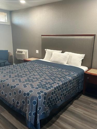Bett in einem Hotelzimmer mit blauer Tagesdecke in der Unterkunft ROYAL MOTEL TRACY in Tracy