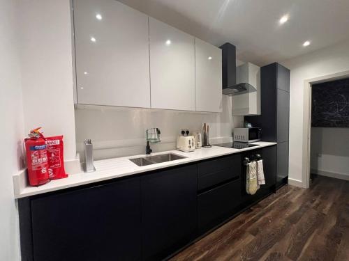 a kitchen with black and white cabinets and a sink at Star London Finchley Road 2-Bed Residence in London