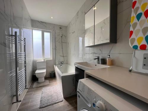 a white bathroom with a sink and a toilet at Star London Finchley Road 2-Bed Residence in London