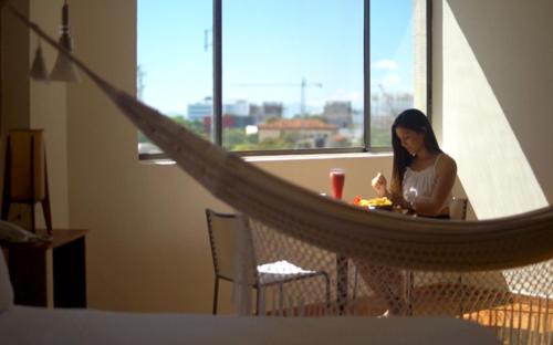 Eine Frau, die an einem Tisch in einer Hängematte sitzt. in der Unterkunft Hotel Sicarare in Valledupar