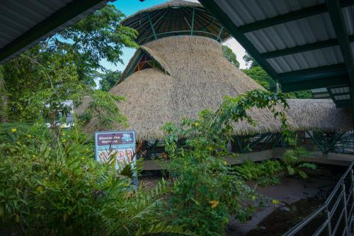 a building with a straw roof with a sign in front at Hotel Serendipity in Tortuguero