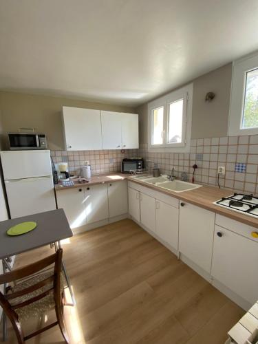 a kitchen with white cabinets and a sink and a table at La maison d'Auguste in Blaudeix